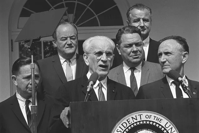 Democratic Congressional leaders give statement to the press after breakfast meeting on Vietnam with Pres. Lyndon B. Johnson. Posing behind podium (L-R) Congr. Carl Albert, V.P. Hubert Humphrey, Speaker John McCormack (speaking), Congr. Hale Boggs, Sen. George Smathers, Sen. Mike Mansfield. Rose Gar. Why war and peace speeches sound the way they do
